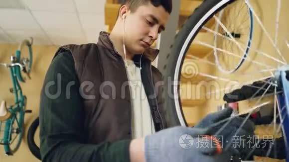 集中的机械师检查旋转自行车轮，然后用特殊工具固定辐条，同时维修自行车和