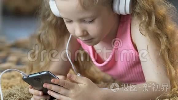 小女孩躺在地毯上，用手机听耳机听音乐