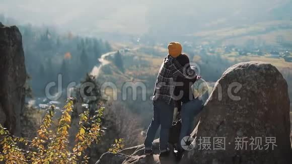 年轻的旅游夫妇相爱，站在岩石上，欣赏美丽的景色。 拜访著名游客的男人和女人