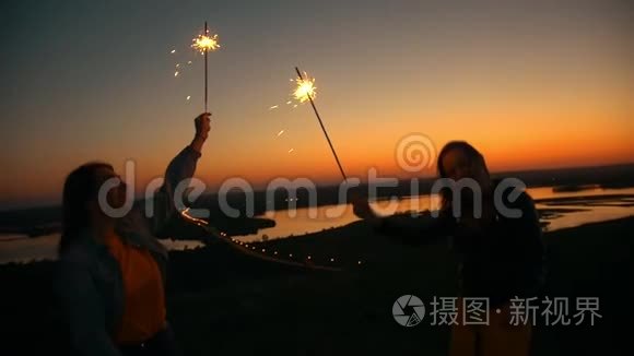 夏天的日落时分，两个快乐的年轻女子在小山上跳舞