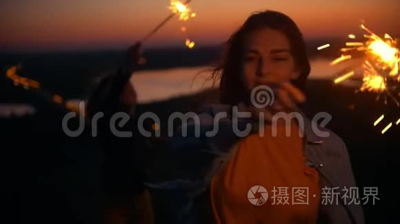 夏日日落时，快乐的年轻女子在山上玩火花
