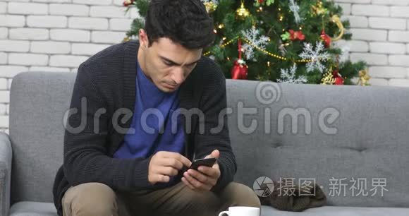 高加索男人在沙发上用智能手机。
