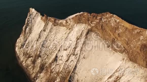 鸟瞰棕色山坡被雪覆盖近海面深蓝色的水.. 中枪。 美丽的风景