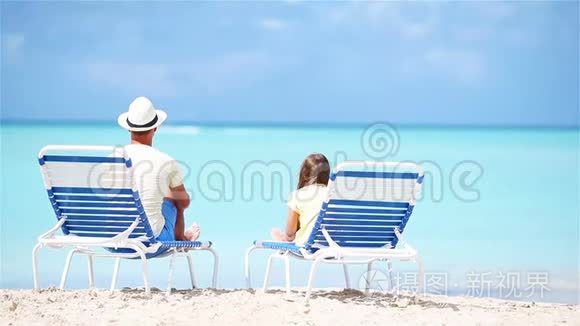 父亲和女儿坐在沙滩上的躺椅上视频