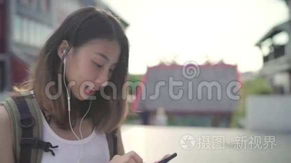 亚洲背包客博主女性使用智能手机聊天，查看社交媒体，在唐人街旅游时听音乐。