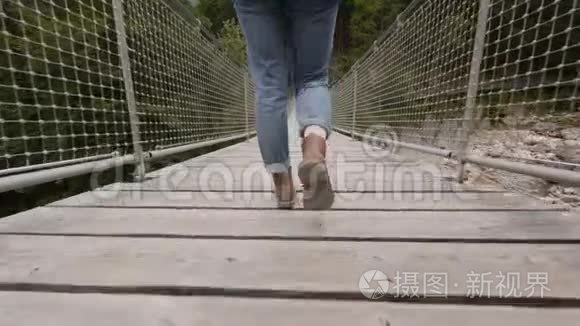 穿牛仔裤和靴子的女人走在桥上