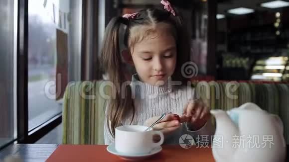 漂亮的小女孩正在咖啡馆里吃午饭。 女婴吃糖果和调味茶