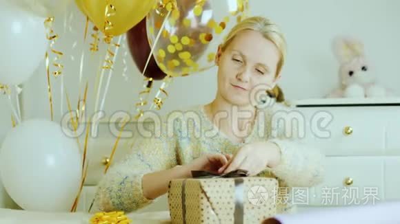 一个女人正在为孩子的生日准备礼物。 把丝带和蝴蝶结粘在盒子上。 在孩子们房间里
