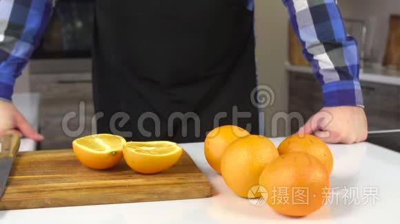 厨房里穿围裙的男人，桌子上摆着橘子，健康的食物，饮食，慢节奏，生活方式