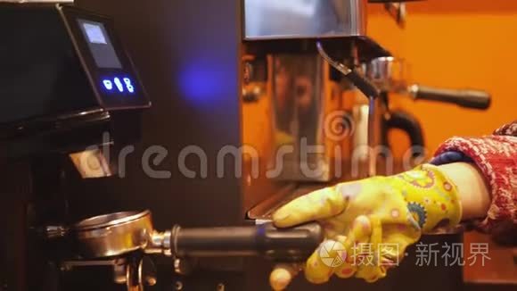 男人或女人咖啡师`双手戴着黄色手套，用现代咖啡机在现代咖啡机里磨咖啡豆