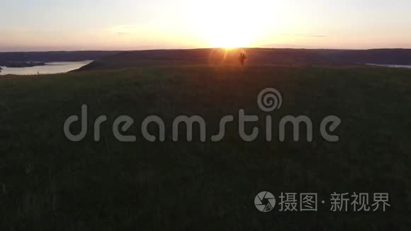 空中飞行在男人的上方，把他幸福的女人紧紧地抱在河岸边。 穿着漂亮红裙子的女人