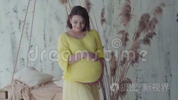 孕妇站在家时抱着肚子。 慢动作