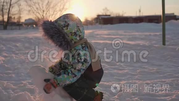 一个小孩在冬天的公园里玩雪.. 阳光明媚的冬天`白天。 新鲜空气中的乐趣和游戏。