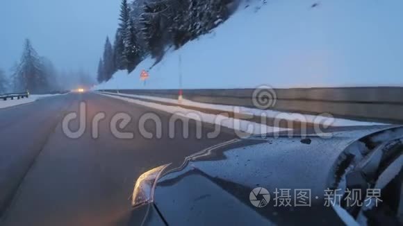 黑暗的现代汽车与前灯在道路上沿雪覆盖的树木。