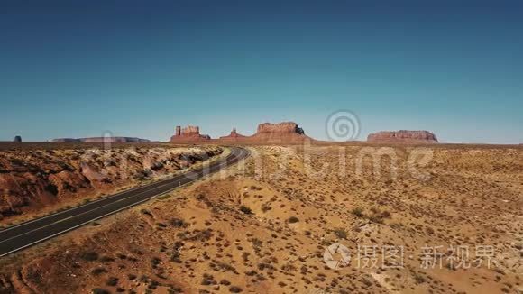 无人机在空沙岩沙漠公路上左转，在亚利桑那州的纪念碑谷，有史诗般平坦的山脉。