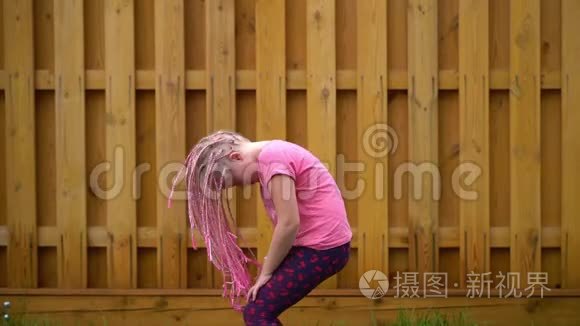 时髦女孩在砖墙附近挥舞非洲辫子-慢动作
