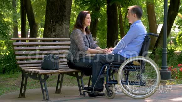 坐轮椅的年轻人在公园里和妻子聊天