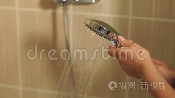 一个女孩的特写镜头在淋浴间打开水。
