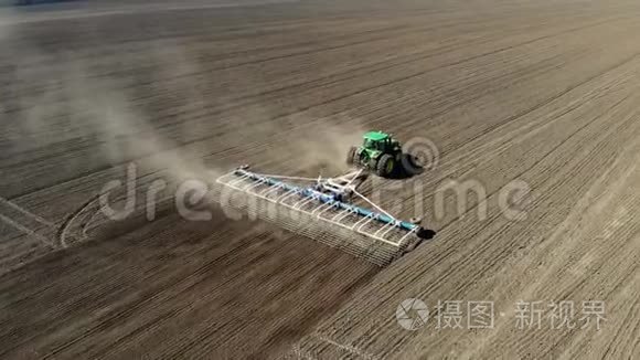 农业耕作拖拉机在大轮犁上的空中视野，在肥沃的农田上耙土，饲养