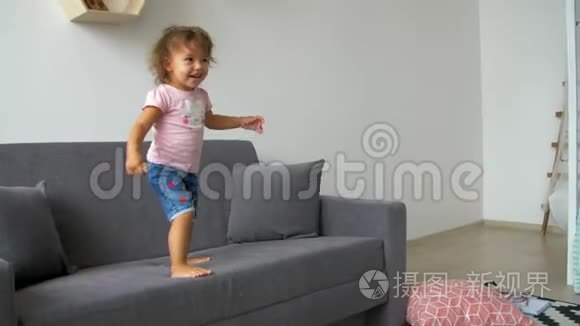 一个小女孩正从沙发上跳过去视频