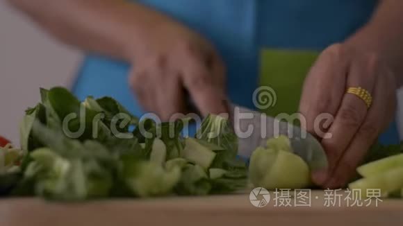 近镜头的女人手切婴儿博克霍伊在木切割板上的健康食品在桌子上。