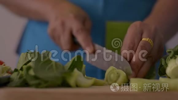 近镜头的女人手切婴儿博克霍伊在木切割板上的健康食品在桌子上。