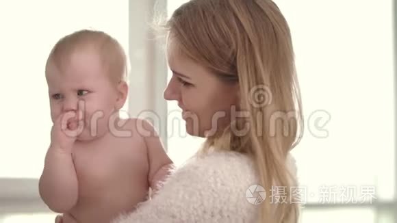 妈妈手上有个伤心的孩子。 年轻的母亲抱着婴儿拥抱