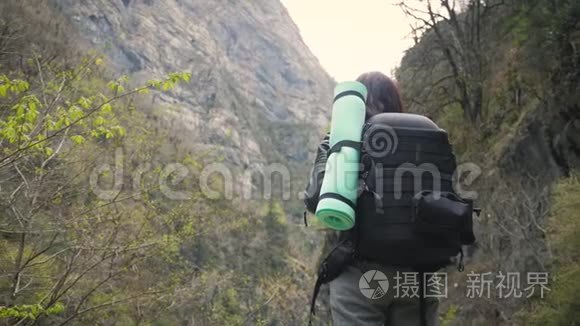 徒步旅行者女士背着背包在山上和山河湖上寻找，女孩在旅途中欣赏大自然的全景