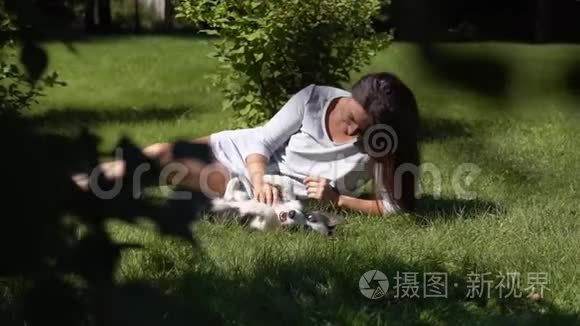 有长发的小女孩在草地上的公园里和一只小狗玩。慢动作。
