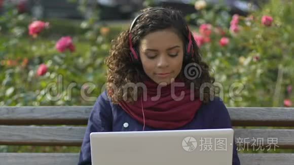 美丽的多种族女孩耳机听音乐笔记本电脑，音频应用程序