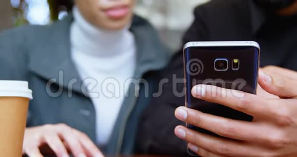 一对夫妇在4k的户外咖啡馆用手机视频的预览图