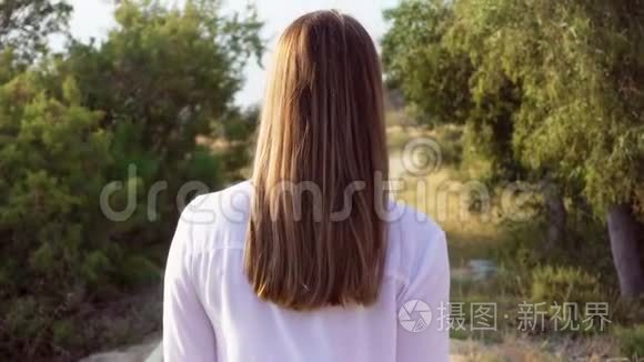 女人在公园的人行道上慢悠悠地走着。 女旅行者转身向男朋友微笑