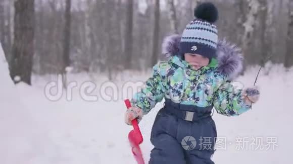 一个小孩在冬天的公园里玩雪.. 阳光明媚的冬天白天。 新鲜空气中的乐趣和游戏。