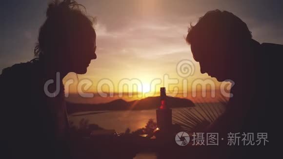 年轻漂亮的夫妇使用智能手机休息在户外海滩咖啡馆喝啤酒在惊人的日落。 3840x2160