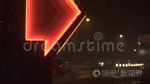 雪片在夜间落在红色霓虹灯的发光箭头引导到加油站与道路的背景。