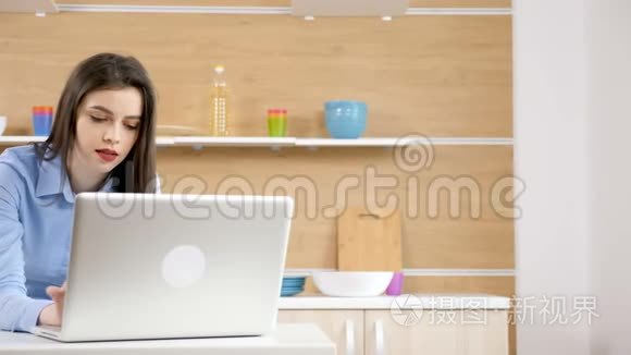 厨房里拿着笔记本电脑的女人在上面打字，然后看着电话
