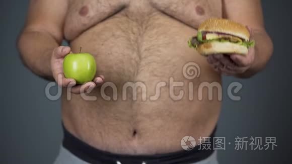 胖子选择苹果而不是汉堡包，保持健康的饮食，腹部特写