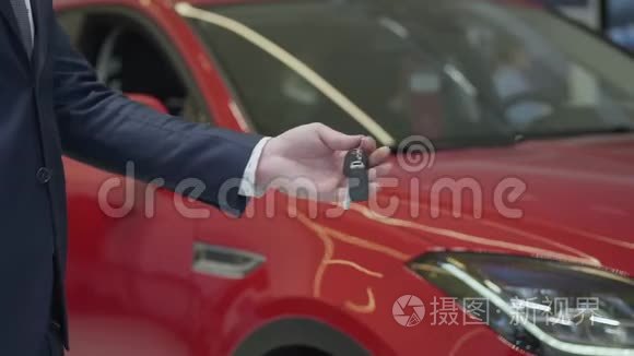 未识别的推销员给未识别的女商人一把汽车钥匙，并在汽车经销商中握手。 汽车陈列室