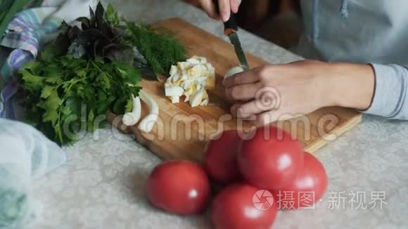 在木板上用刀切煮鸡蛋，把女人的手收起来。 食物概念