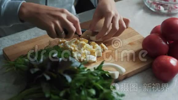 在木板上用刀切煮鸡蛋，把女人的手收起来。 食物概念