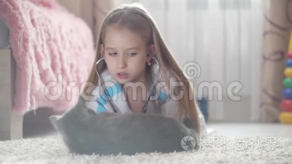 小女孩在家和猫玩医生。 女孩扮演兽医与家庭宠物。