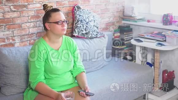 年轻无聊的女人坐在家里的沙发上看电视。 4k