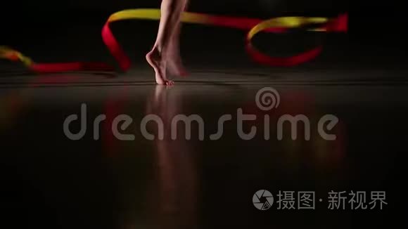 女运动员用彩带表演艺术体操元素的特写、纤细的腿