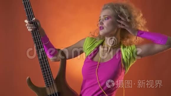 金发的80年代迪斯科舞者，用吉他摆姿势，橙色背景