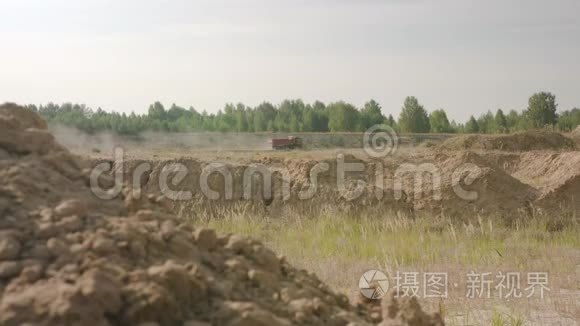 卡车在尘土飞扬的道路上行驶到采石场。 场景。 以土堤为背景，卡车在田间道路上行驶