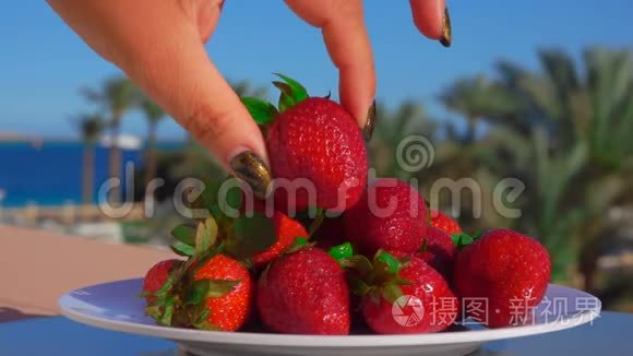 手从盘子里拿出一大块多汁的草莓