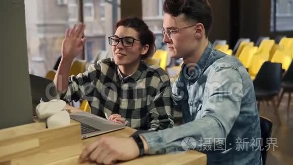 两个戴着眼镜的年轻人坐在一起，通过视频聊天与某人交谈