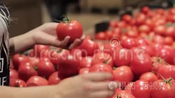 女`的手在超市里挑选西红柿。