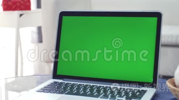 显示绿色色度键屏幕的笔记本电脑站在客厅的桌子上。 放大