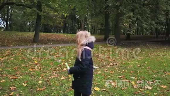 一个女学生在秋天的公园里玩肥皂泡。